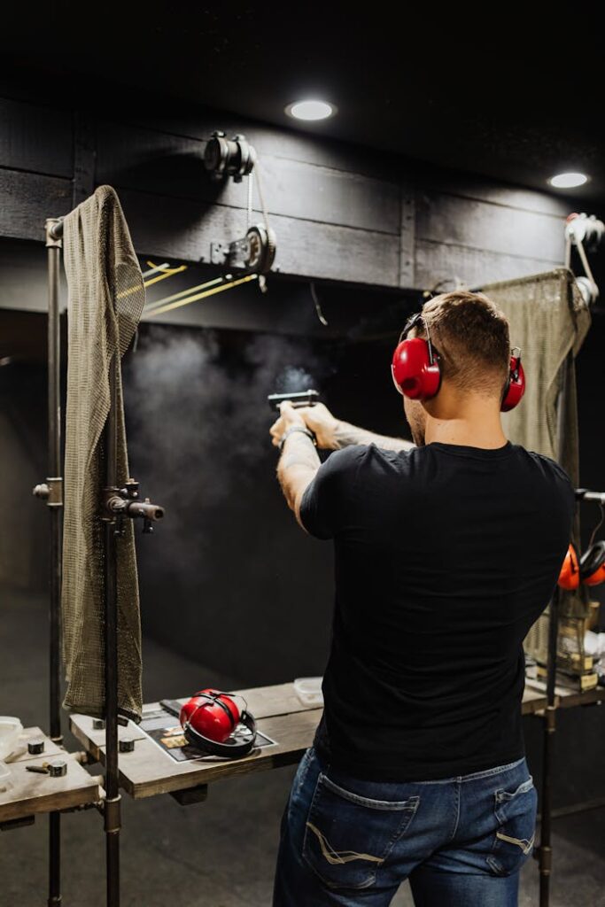pexels-photo-5202445 A man with ear protection shooting a pistol at a firing range indoors.